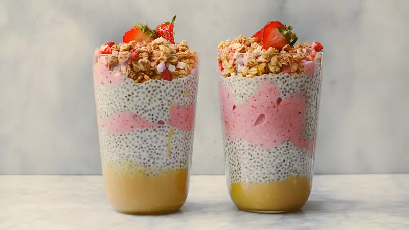Chiapudding och smoothie i glas toppad med granola och färska jordgubbar